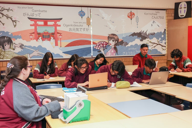 Students working in the Languages classroom using laptops with decorated window blinds