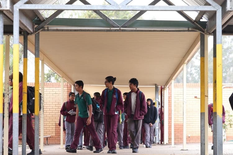 Large group of students walking into the main entrance of the school quad