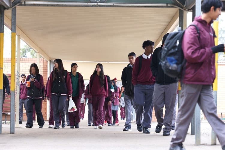 Multiple groups of students with bags and backpacks moving to class in different directions