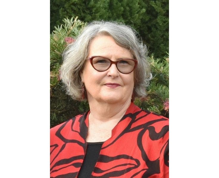 Photo of Karyn O'Brien wearing a red and black top with a green bush background